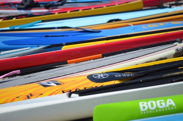 bright blue, yellow, lime green, and white paddle boards and canoes 